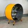 Gelbes Flaschenregal 'Jil' aus upcycling Ölfass Möbel von Tonnen Tumult, mit Flaschen dekoriert, vor der Wand von rechts