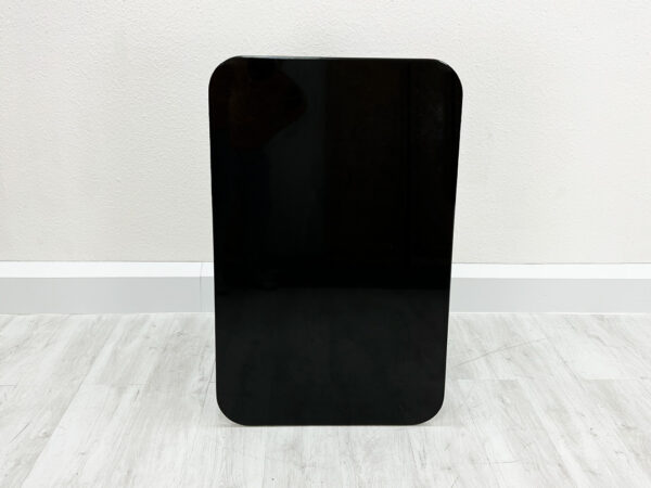 Schwarze aufrechtstehende rechteckige Granit Tischplatte mit abgerundeten Kanten auf weißem Holzboden vor weißem Hintergrund