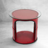 Roter runder upcycling Tisch mit Glastischplatte aus rotem Oelfass und schwarzem Kantenschutz vor grau meliertem Hintergrund