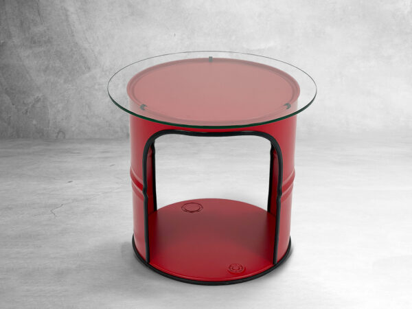 Roter runder upcycling Tisch mit Glastischplatte aus rotem Oelfass und schwarzem Kantenschutz vor grau meliertem Hintergrund
