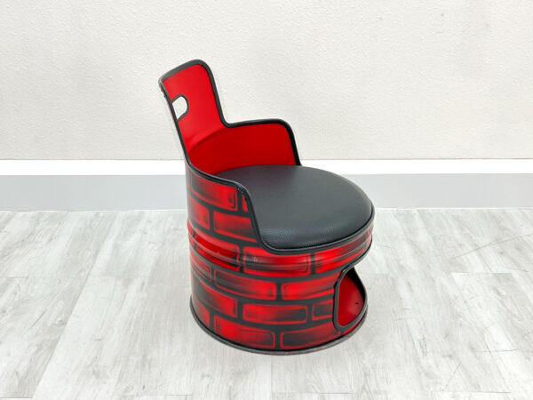 Oelfass Sessel in roter Grundfarbe mit aufgesprayten Backsteinen, schwarzem Sitzpolster, schwarzem Kantenschutz und Stauraum unter der Sitzflaeche vor weißem Hintergrund
