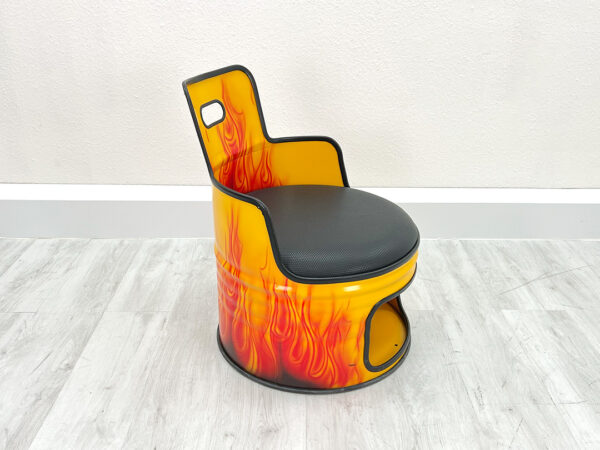 Oelfass Sessel in gelber Grundfarbe mit aufgesprayten Flammen, schwarzem Sitzpolster, schwarzem Kantenschutz und Stauraum unter der Sitzflaeche vor weißem Hintergrund