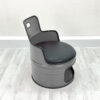 Grauer Oelfass Sessel mit schwarzem Sitzpolster, schwarzem Kantenschutz und Stauraum unter der Sitzflaeche vor weißem Hintergrund