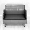 Sofa aus Oelfass in Grau von Vorne mit schwarzer Polsterung und schwarzem Kantenschutz auf weißem Holzboden vor weißer Wand