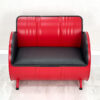 Sofa aus Oelfass in Rot von Vorne mit schwarzer Polsterung und schwarzem Kantenschutz auf weißem Holzboden vor weißer Wand