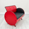 Rotes Oelfass Sofa mit schwarzer Polsterung, halbseitliche Ansicht, auf weißem Holzboden vor weißer Wand