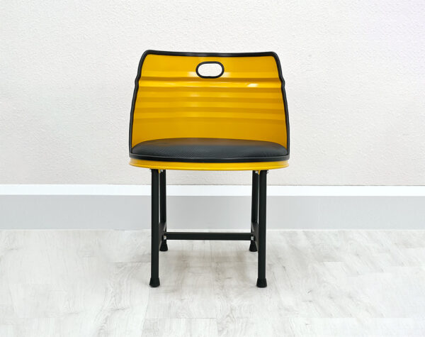 Gelber Stuhl Liam aus Oelfass von Vorne mit schwarzem Kantenschutz, schwarzem Polster und Beinen vor weißer Wand