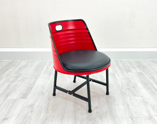 Upgecycelter Oelfass Esszimmer Stuhl in Rot mit schwarzem Sitzpolster, schwarzen Metallbeinen und schwarzem Kantenschutz auf weißem Holzboden vor weißem Hintergrund