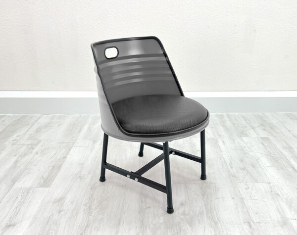 Esszimmer Stuhl aus Oelfass in Grau mit schwarzem Sitzpolster, schwarzen Metallbeinen und schwarzem Kantenschutz auf weißem Holzboden vor weißem Hintergrund