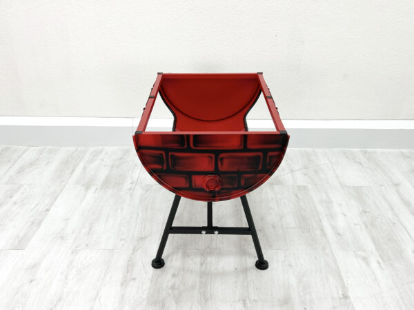 Tischgestell Mick in Rot mit aufgesprayten Backsteinen ohne Tischplatte auf Metallfueßen vor weißer Wand auf weißem Holzboden