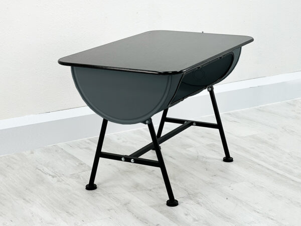 Fass-Esstisch Mick aus einem halben grauen Oelfass mit Granit Tischplatte auf schwarzen Beinen vor weißer Wand auf weißem Holzboden