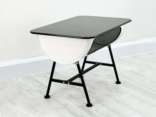 Tisch bestehend einem geteilten Oelfass in Weiß auf schwarzen Stahlbeinen und schwarzer Granit Tischplatte vor weißer Wand auf weißem Holzboden
