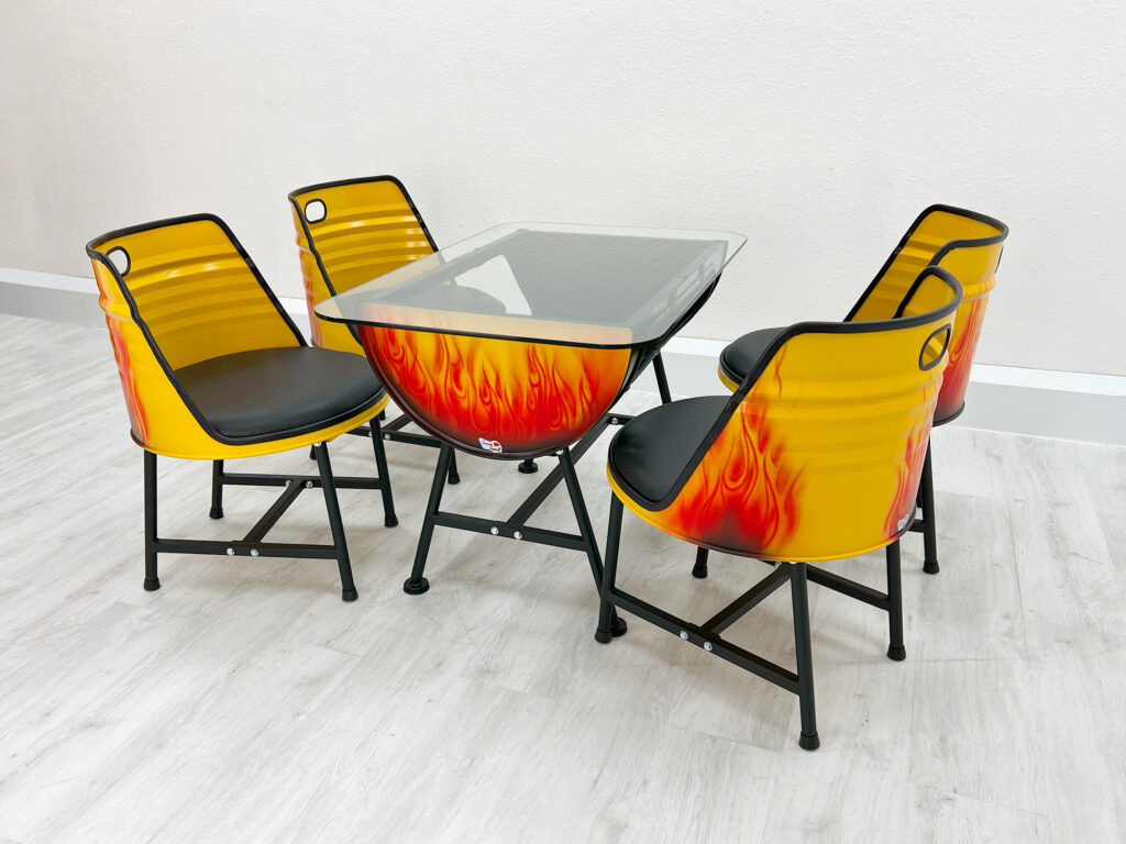 Ölfass Tisch und vier Stühle in Gelb mit roten Flammen und schwarzen Beinen auf weißem Holzboden.