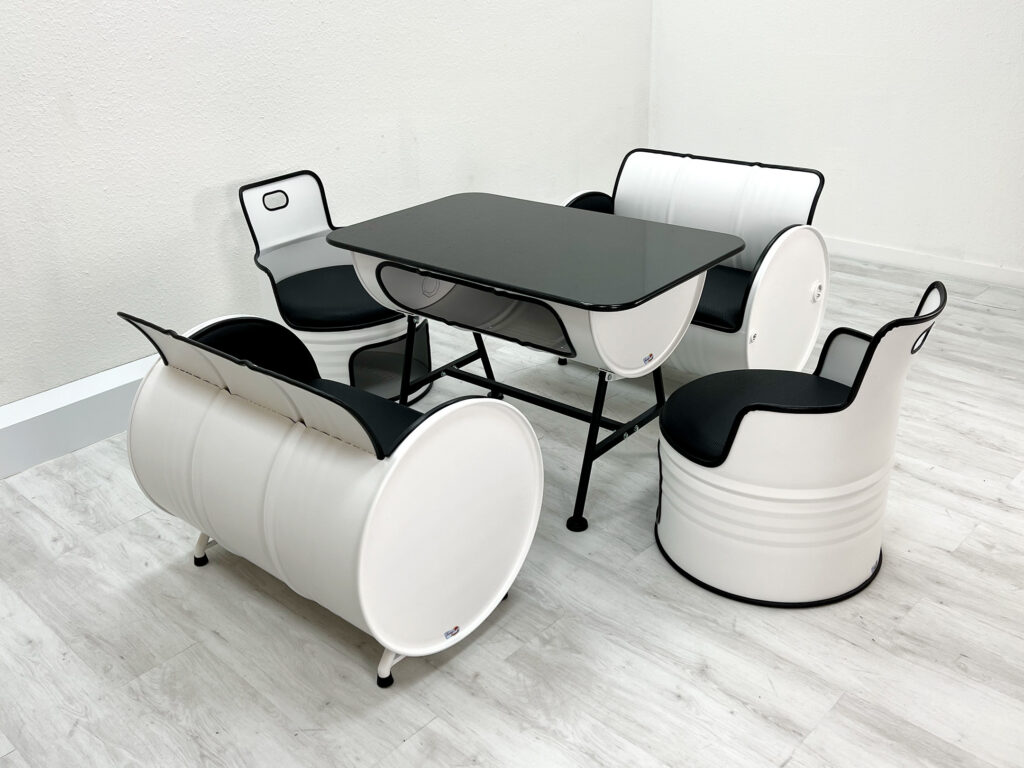 Ölfass Sitzgruppe in Weiß mit schwarzen Sitzpolstern, bestehend aus zwei kleinen Sofas, zwei Sesseln und einem Tisch mit Granitplatte auf weißem Holzboden.