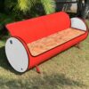 Rot-weißes Sofa 'Joy' von Tonnen Tumult, geschickt upcycelt aus einem Oelfass und stilvoll platziert in einem Wohnzimmer.
