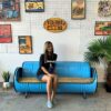 Frau sitzt auf hellblauem Ölfass Sofa 'Joy' von Tonnen Tumult